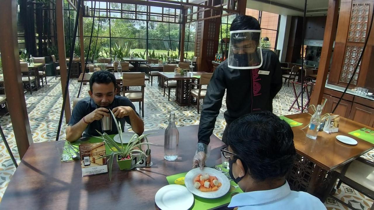 浦那兰花酒店 外观 照片 A restaurant in India with a waiter wearing a face shield